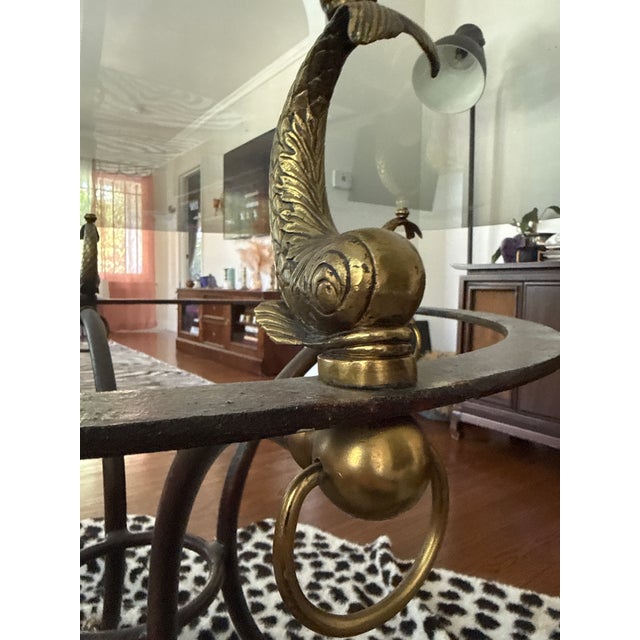 Vintage Hollywood Regency style round glass dining table with sculptural dolphin/koi fish accents, brass-tone details,...