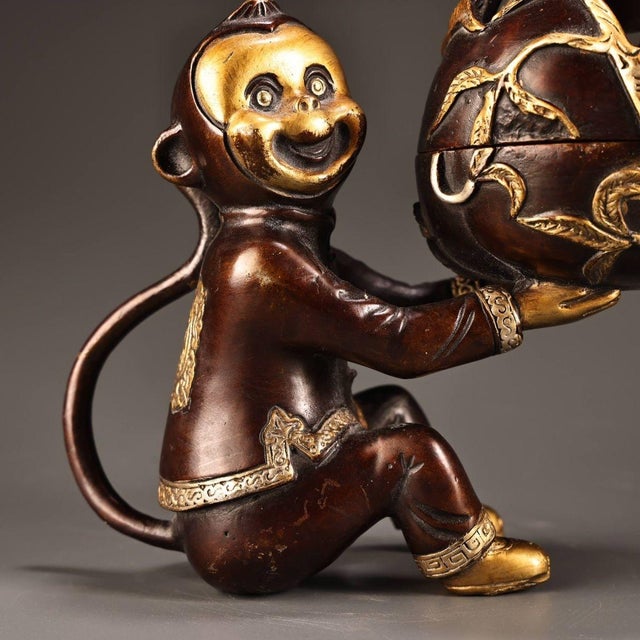 This is a charming vintage Chinese bronze incense burner (censer) featuring a whimsical monkey holding a large, oversized...