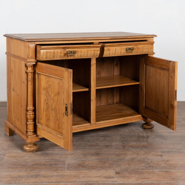 Danish pine sideboard with carved leaf pattern along front door panels. Doors are flanked by elaborate turned columns and...