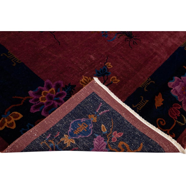 Beautiful antique Art Deco Chinese hand-knotted wool rug with a burgundy field. This Chinese rug has a navy-blue frame...