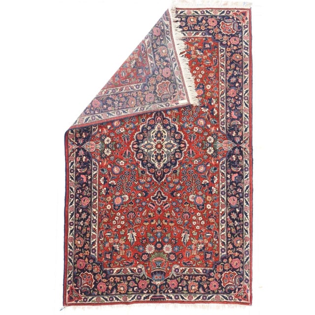 The crisp red field, with a wide variety of Persian garden flowers, flows around the small lightly scalloped navy...