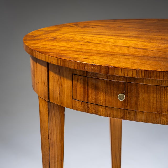 Biedermeier table in cherrywood with an oval top and a single drawer integrated into the plain apron. The table stands on...