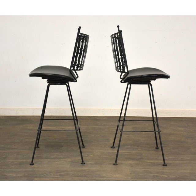 A pair of mid century modern iron bar stools in the style of Arthur Umanoff. Some marks and discoloration in seat. Seat...