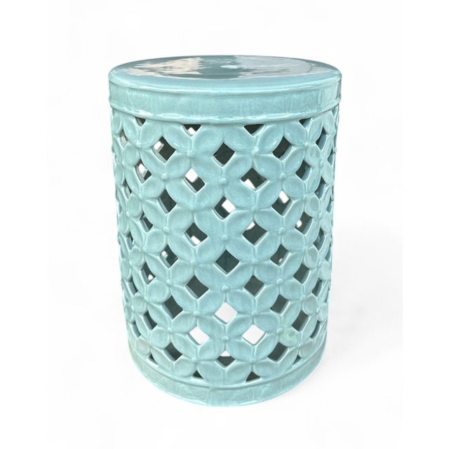 The Cherise Garden Stool is a ceramic garden stool with a cylindrical form and an allover flower-of-life pierced pattern...