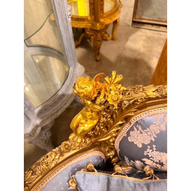 French Louis XVstyle canapé settee, beautifully crafted with an elaborately carved frame, rich gold finish, and elegant...