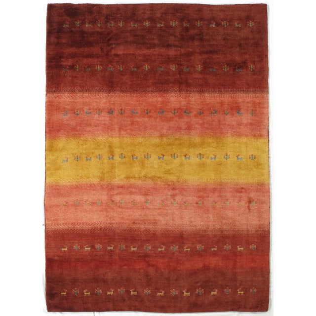 Vintage Hand-knotted Persian Lori Gabbeh rug featuring horizontal bands in rich shades of red, rust, and golden yellow....