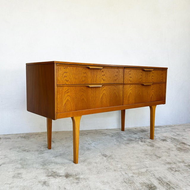 Compact teak sideboard by Frank Guille for Austinsuite, England circa 1960s. Four drawers arranged as two pairs with...