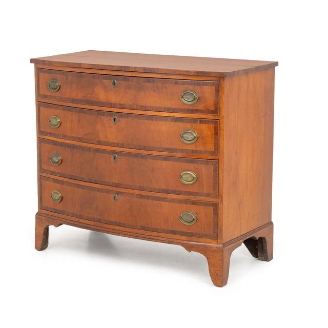Late George III English chest of drawers crafted in fruitwood with contrasting crossbanded drawer fronts and top. Features...