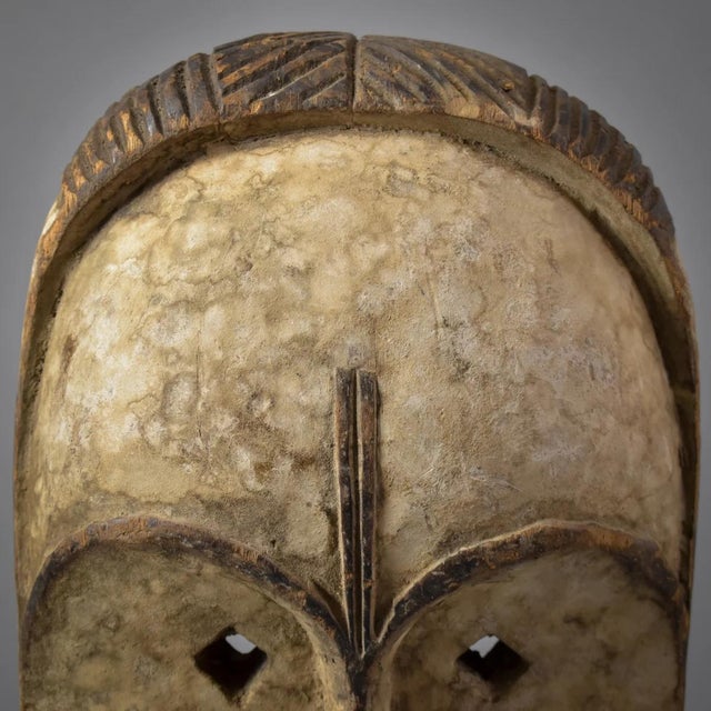 The Fang face mask, displaying wear both on its surface and interior, signifies its age and extensive use.Â It is crafted...