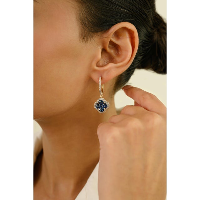 These elegant drop hoop earrings feature 10 oval and square cut blue sapphires totaling 4.55 carats, set in 14k yellow...