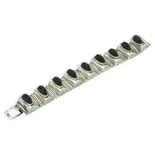 This is a Mexico silver statement bracelet with Aztec-themed faces. The vintage hinged bracelet has nine carved black...