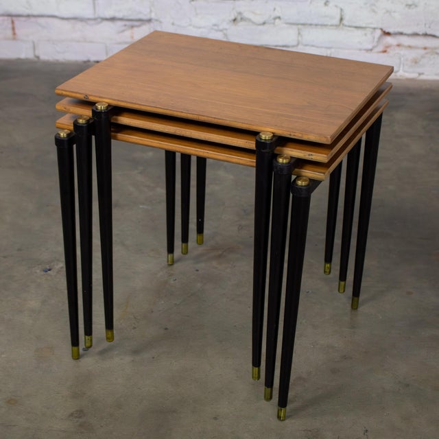 Wonderful vintage MCM or Mid Century Modern stacking tables composed of walnut veneer rectangular tops, ebonized legs with...