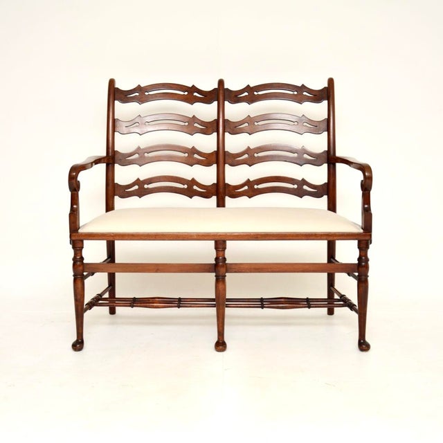 A wonderful antique ladderback settee, made in England, and dating from around the 1820-1850 period. It is of superb...