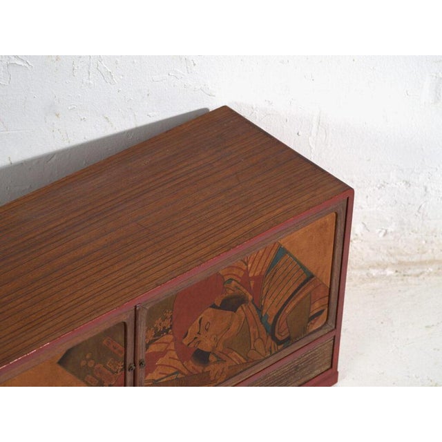 Small Japanese cabinet with decorated sliding doors crafted from paulownia wood (Paulownia spp.), originating from Japan...