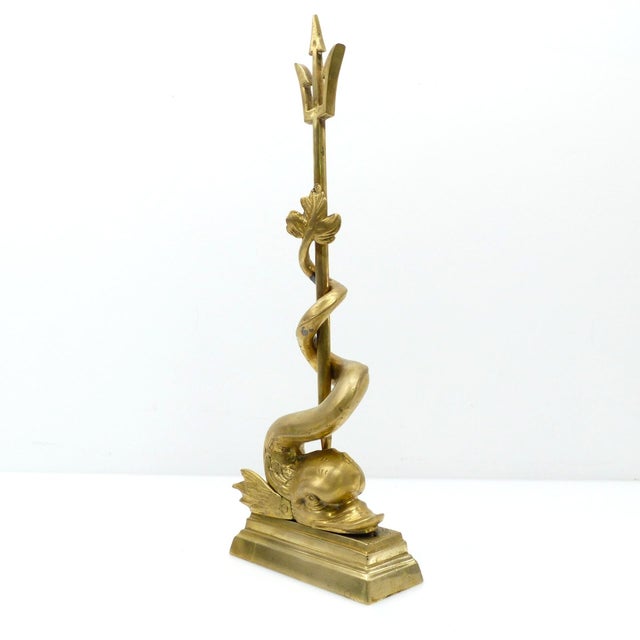 Large decorative doorstop in patinated cast brass, depicting a fantastical dolphin whose long tail is coiled around...