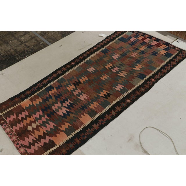 Handwoven in fine wool, a 5x10 vintage Persian kilim originating circa 1950-1960. An intriguing piece from the mid-...