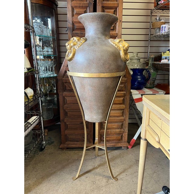 Large earthenware ceramic amphora vase with lions & stand. The urn shape vase has three Lion head ring handles. The vase...