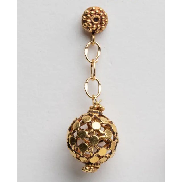 An unusual pair of 18K gold dimpled ball earrings dangling from a gold chain and granulated gold post. For pierced ears....