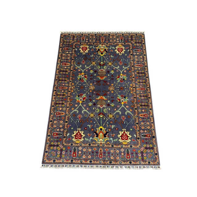 This Sultani wool area rug features a deep slate-blue field filled with symmetrical floral vines and blossoms. Burgundy,...