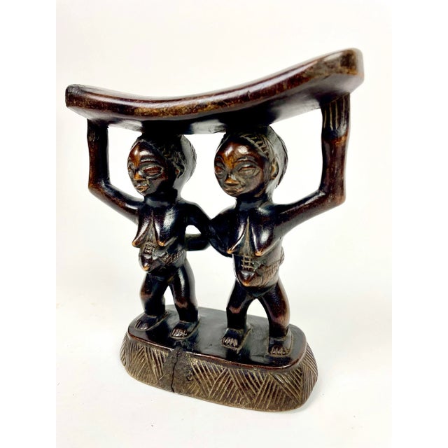 Beautifully carved headrest from the Luba people in central Africa. Couple joining arms and supporting the curved top...