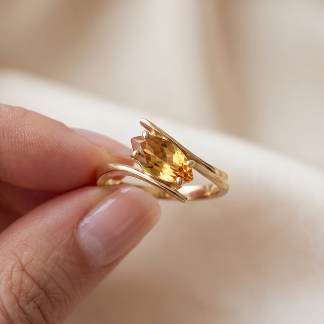 Elevate your style with this elegantly crafted bypass ring featuring a vibrant marquise-cut gemstone set in a modern gold...