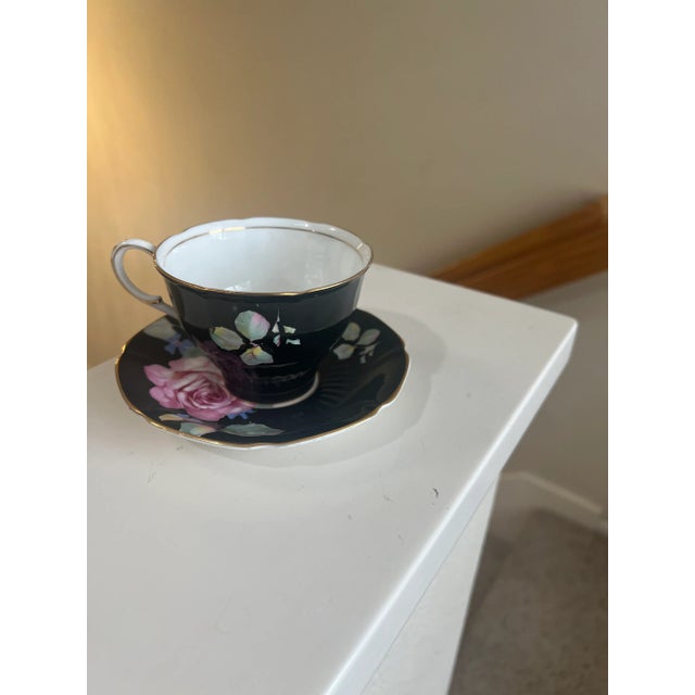 Black on the outside with a floral painting with pink and green. Item is in a good condition no chips