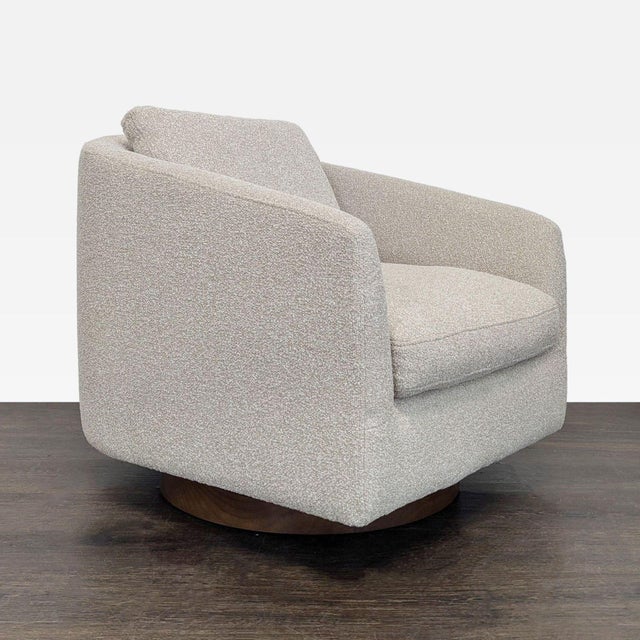 This West Elm lounge chair features a soft, textured beige fabric and a sturdy swivel base. Its thick cushion and...