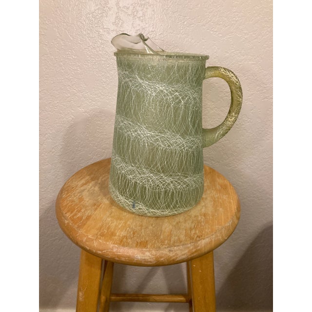 A distinctive 1960s Color Craft Corporation pitcher from the company's innovative Shat-R-Pruf line. The glass body is...