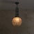 A French Art Deco pendant from the 1920s, defined by a molded glass globe suspended below a wrought iron support. The...