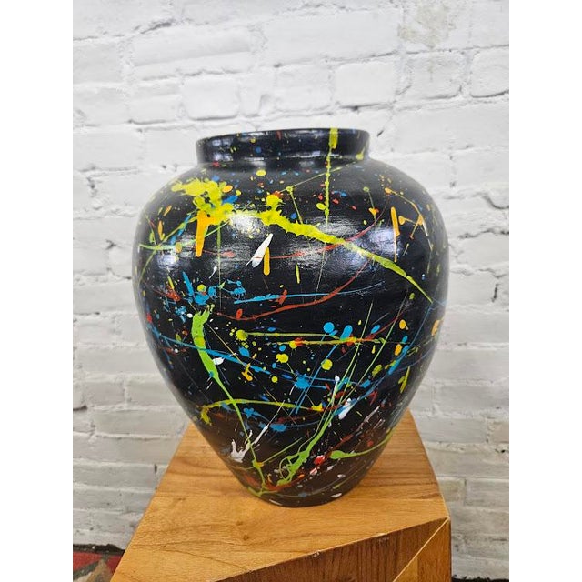 Abstract expressionist ceramic vase featuring a glossy jet-black base, this vessel serves as a dramatic canvas for an...