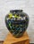 Abstract expressionist ceramic vase featuring a glossy jet-black base, this vessel serves as a dramatic canvas for an...