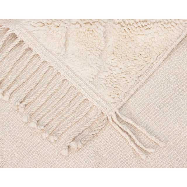 Elegant hand-knotted natural wool rug, featuring a subtle, flat-woven abstract design evoking a sense of fluidity and...