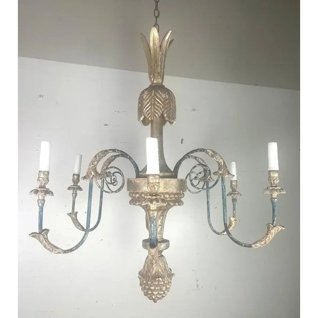 This traditional Italian style chandelier features a central column adorned with a pineapple-like top finial, adding a...