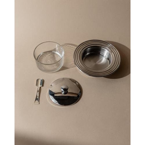 This vintage 1970s glass and stainless steel lidded jar is a refined retro table accessory designed for serving jam,...