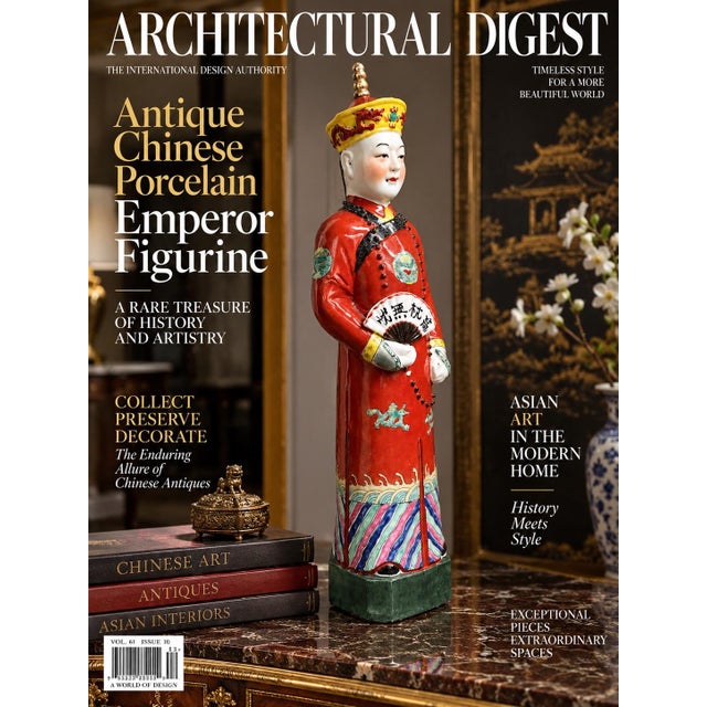 This is a hand-painted porcelain figurine depicting a Qing dynasty emperor dressed in a vibrant red robe with polychrome...