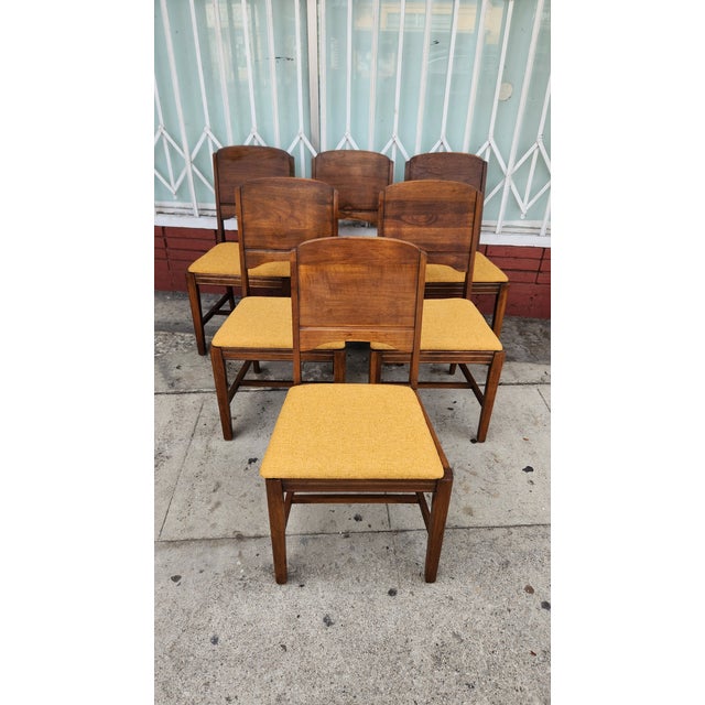 1960's set of six dining chairs constructed from solid wood with a warm brown finish. Each chair has a curved wooden...