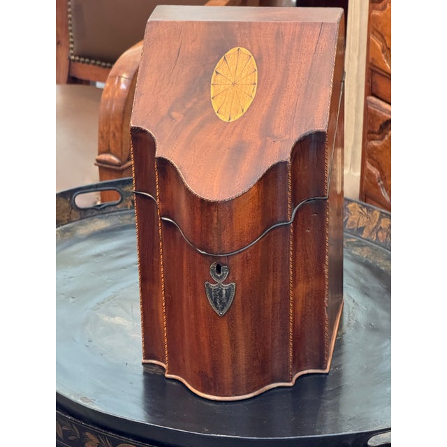 George III knife box of serpentine form with a sloped, hinged lid. The front and lid are centered with inlaid oval paterae...