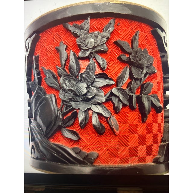 An intricately decorated Chinese-style lidded jar featuring elaborate raised floral carvings against a vibrant red...