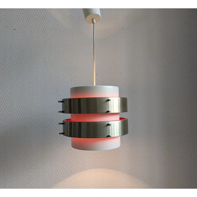 This space age lamp in scandinavian design is a metal pendant lamp from aka ddr from the 1970s. The metal slats in white...