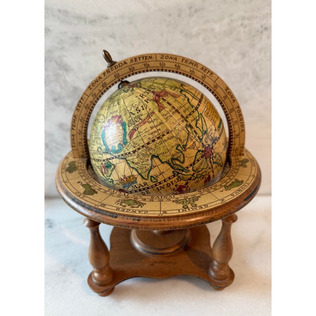 Vintage wood and paper tabletop world globe featuring detailed old world cartography, classical Latin labels, and a...