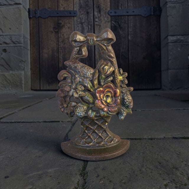 This antique 1920s cast iron flower basket doorstop is marked and numbered, making it a unique and collectible piece....