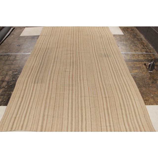 Handwoven in wool, a vintage kilim rug of the 1950s in panel style featuring a striped pattern playing warm and cool in...