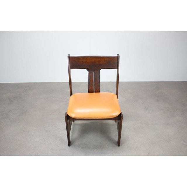 A sculptural vintage chair from Germany, dating to circa 1970, distinguished by its dark-stained wooden frame, angular...