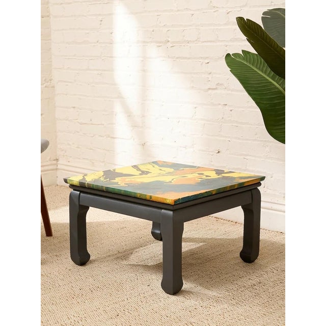 A bold vintage side table with a wildly expressive marbled top swirling with saturated yellow, orange, deep teal, and...
