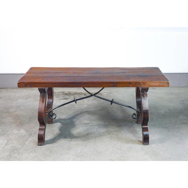Solid walnut table with wrought-iron crossbars and lyre-shaped legs. Italy, 20th century. origin italy period 20th century...