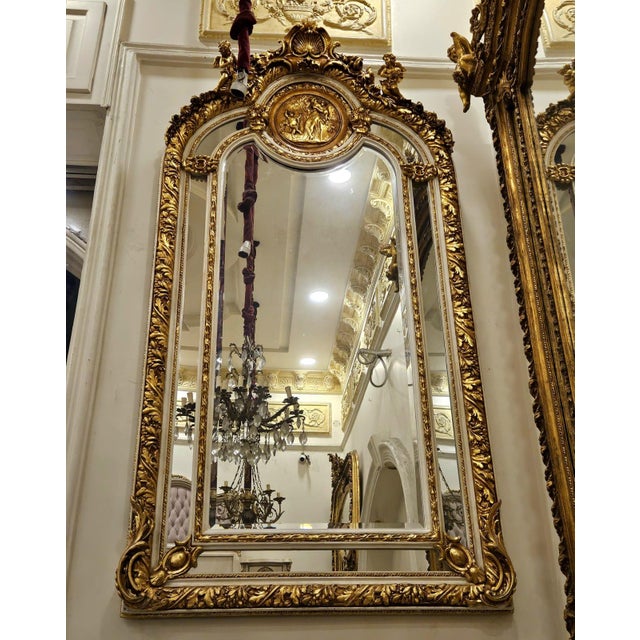 This breathtaking French Baroque style wall mirror features an exceptionally ornate gilded frame adorned with elaborate...