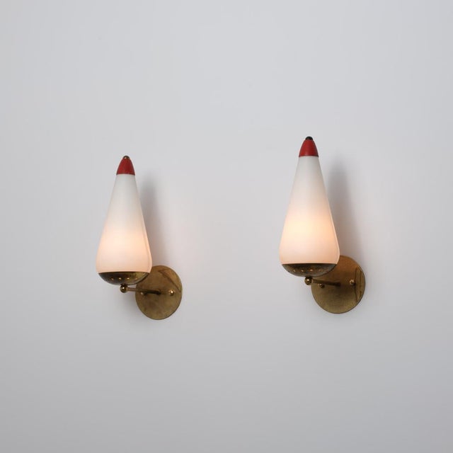 Elegant pair of italian wall sconces from the 1950s, distinguished by their refined tapered silhouette and playful use of...