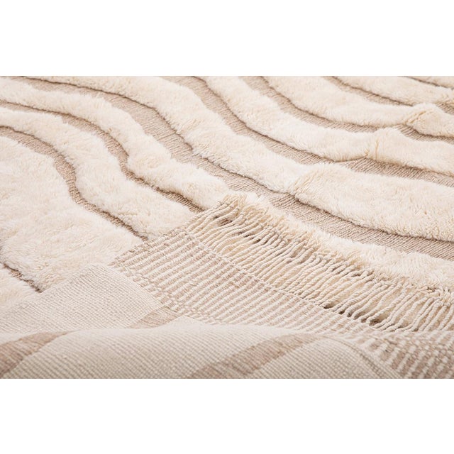 Serenity, woven into every knot. This elegant hand-knotted Moroccan rug features a flowing ripple-like pattern in soft...