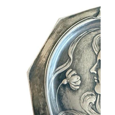 An exquisite Art Nouveau decorative metal plate featuring a beautifully sculpted young woman in profile, framed by...