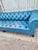 Tufted leather sofa in a vibrant blue color. This Chesterfield style piece has deep button tufting across the back, seat,...